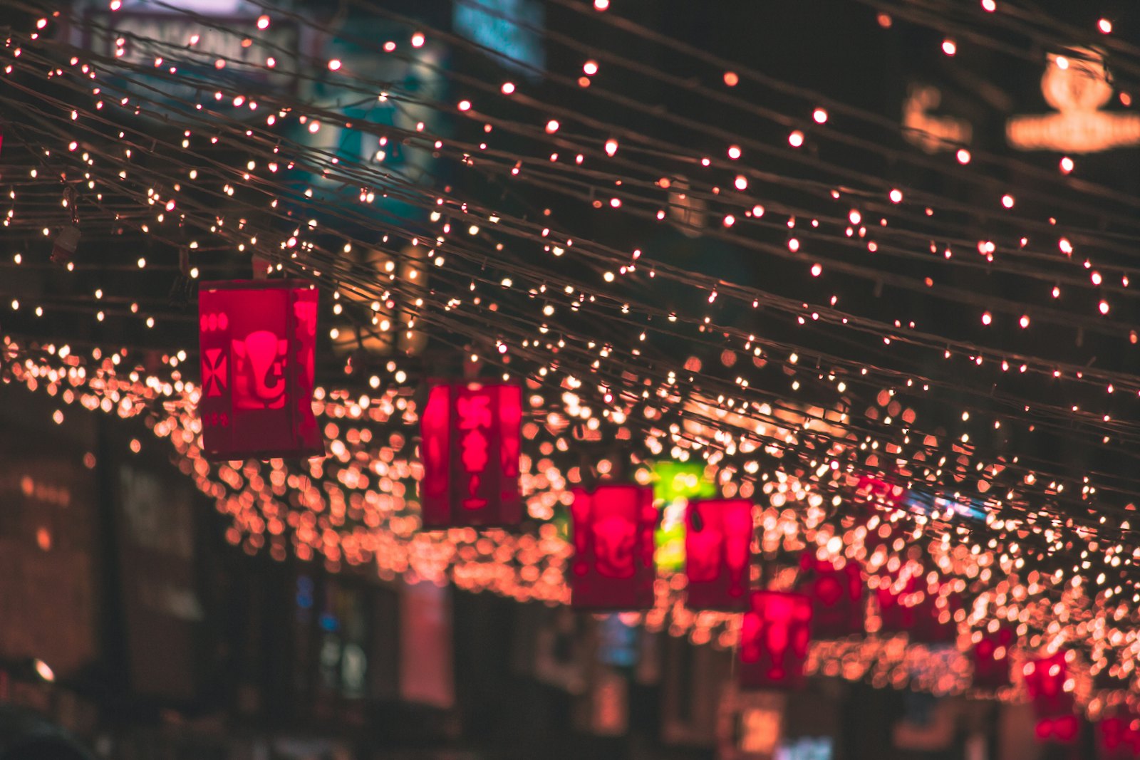 Festive string lights and lanterns strung across a street at night