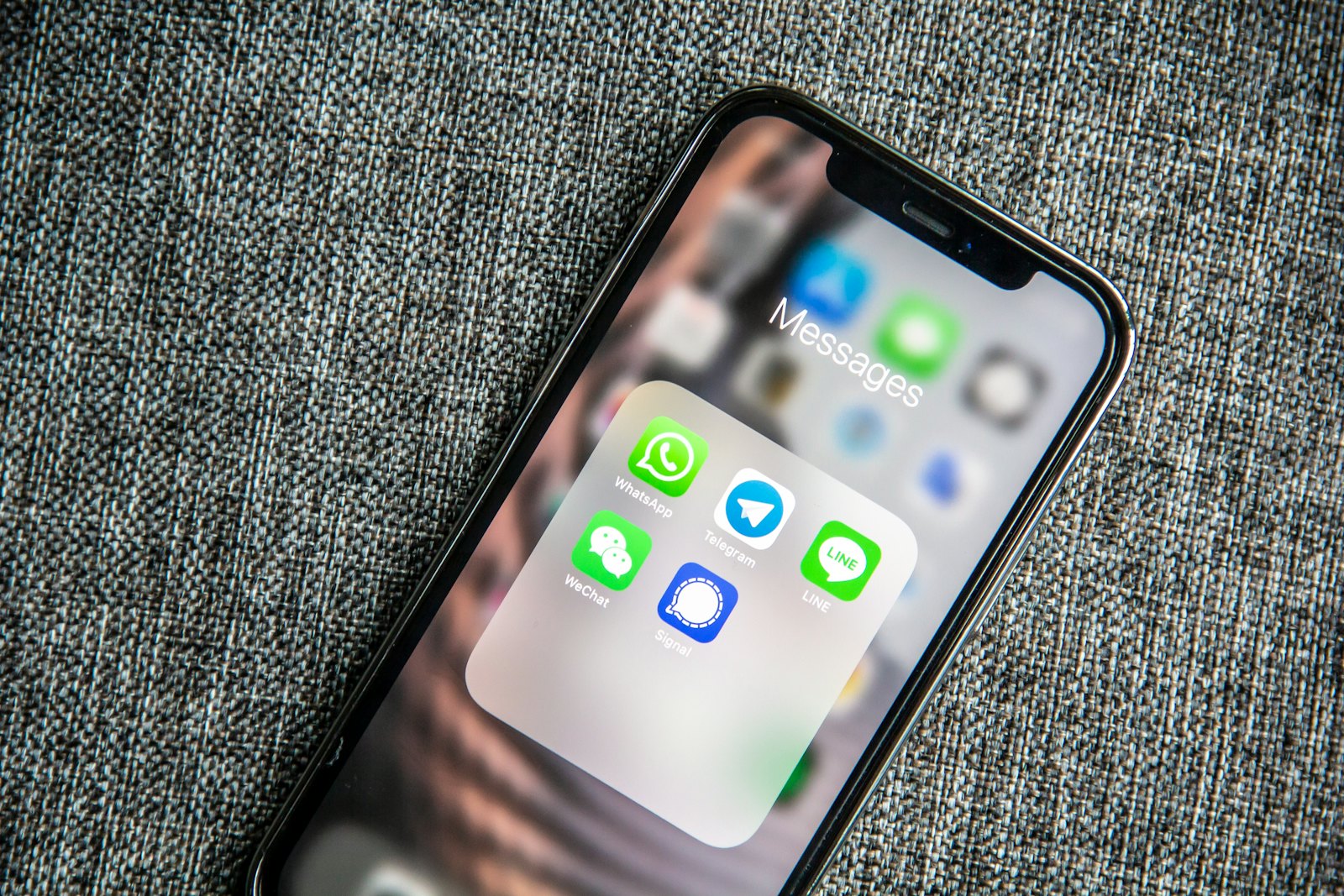 Phone showing a folder of messaging apps with WhatsApp in the foreground